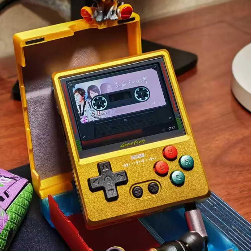 Yellow handheld gaming console with a small screen displaying a video, on a wooden surface.