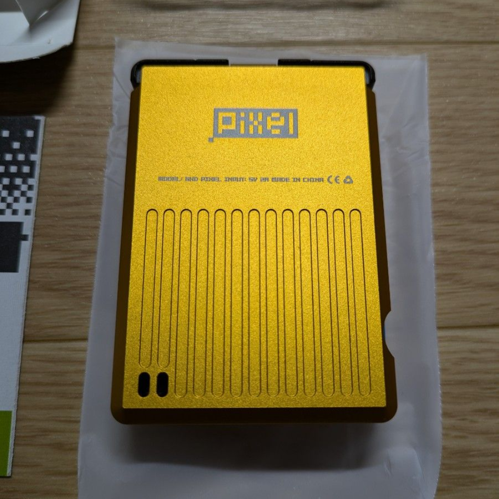 Yellow electronic device with 'Pixie' branding on a wooden surface