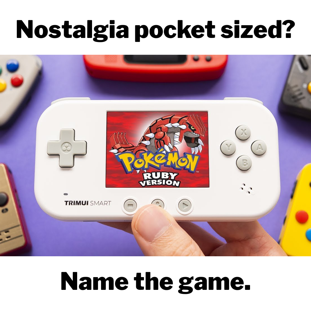 Hand holding a small handheld gaming device with 'Pokémon Ruby' on the screen against a purple background.